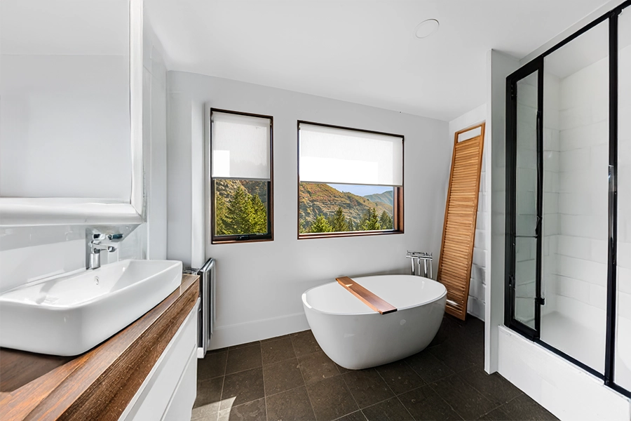 If your bathroom doesn't get excessively damp, a crisp white window shade looks beautiful on a bathtub window. White window shades on bathroom windows