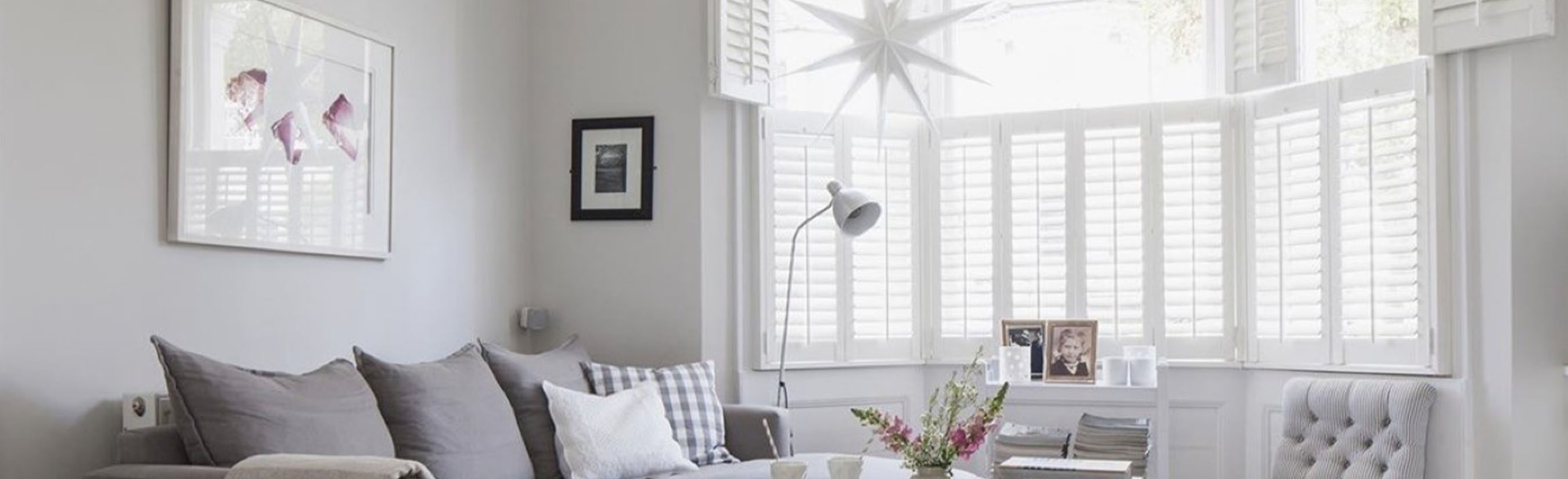 White polywood shutters in a bay window by a living room.