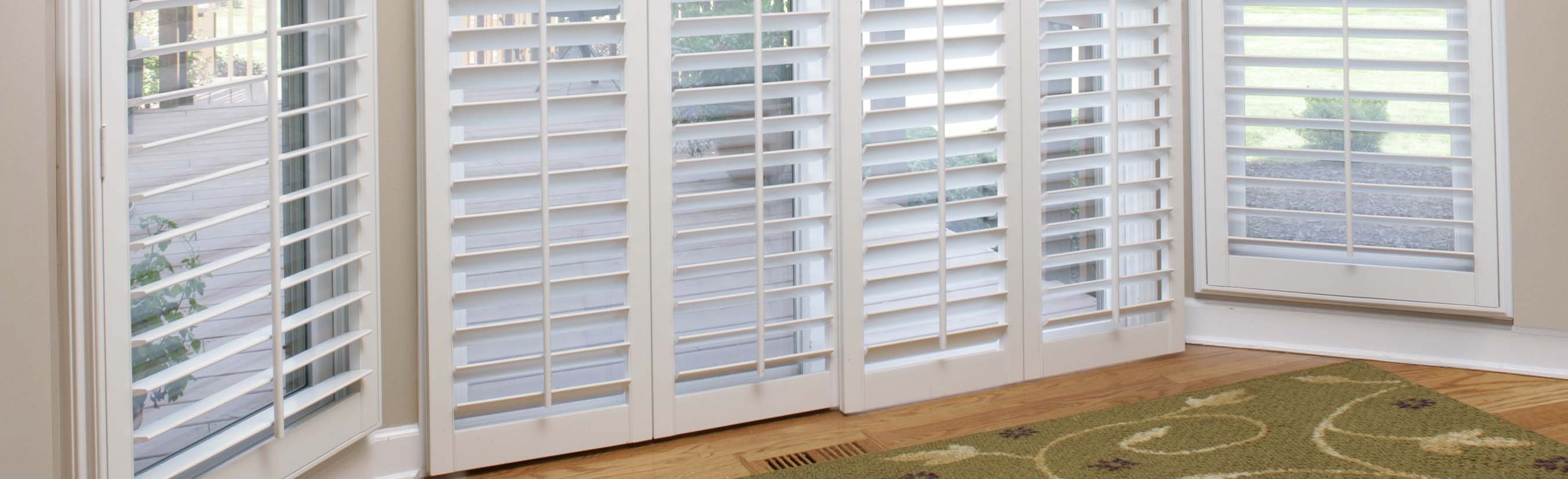 White shutters on a sliding glass door opens to a deck by the ocean.