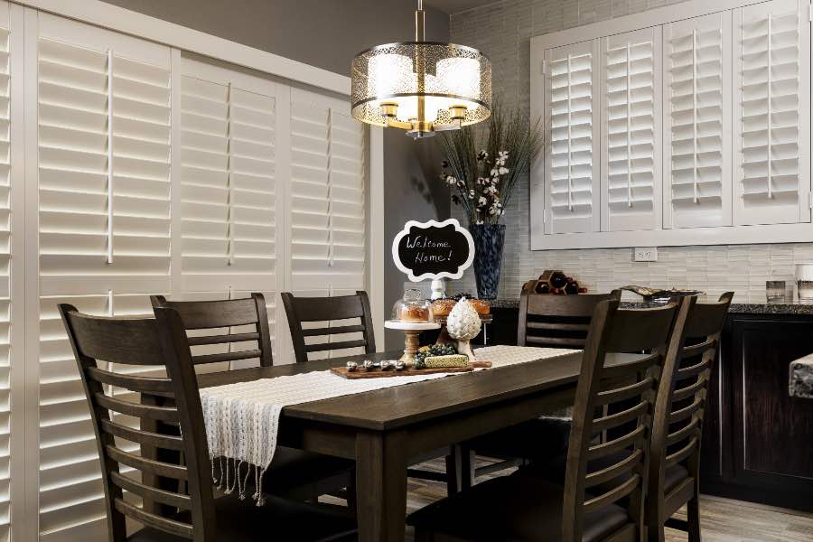 Put energy-efficient Polywood shutters on windows and doors to save on energy costs. Polywood shutters on a sliding door and window in a dining room
