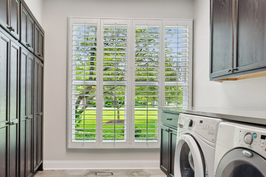 Find the perfect level of natural light for your Cincinnati laundry room with interior shutters. White Polywood shutters letting light through a laundry room window