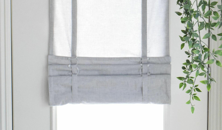 With a tiered tumble shade in Cincinnati, you can block sun glare all year round. Gray rolled tumble shade on a glass door